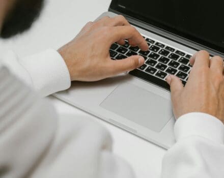 man met baard typt op macbook