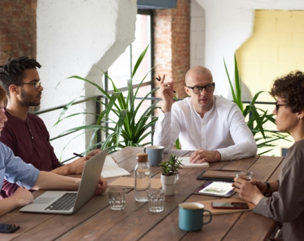 mensen vergaderen aan een houten tafel met laptops daarop