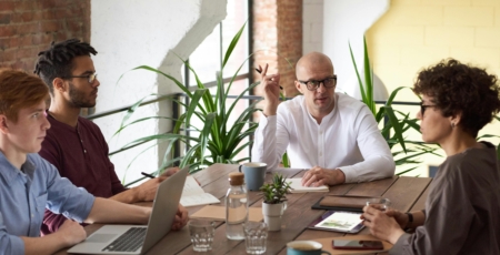 mensen vergaderen aan een houten tafel met laptops daarop