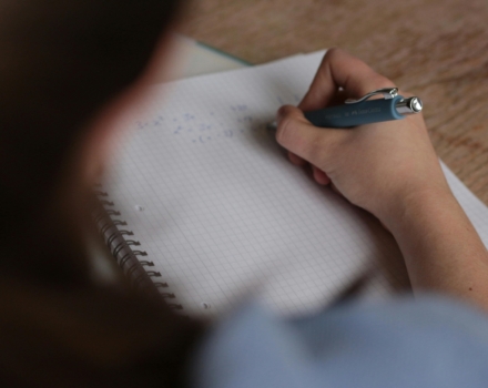 persoon schrijft rekensommen met een blauwe pen