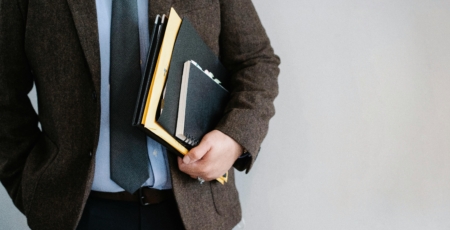 man in bruine jas houdt folders en mappen vast