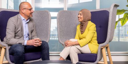 twee medewerkers hebben een gesprek op kantoor, zittend op grijze stoelen